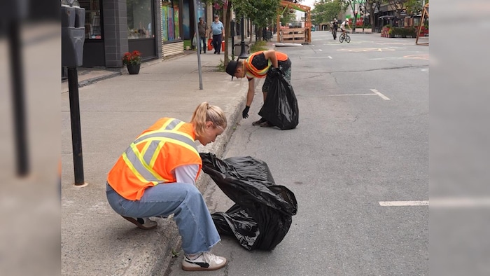 Deux personnes ramassent des déchets au centre-ville de Rouyn-Noranda.