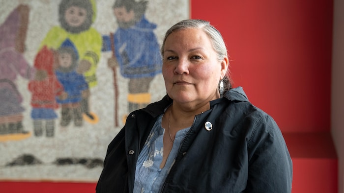 La dame pose devant une murale. 