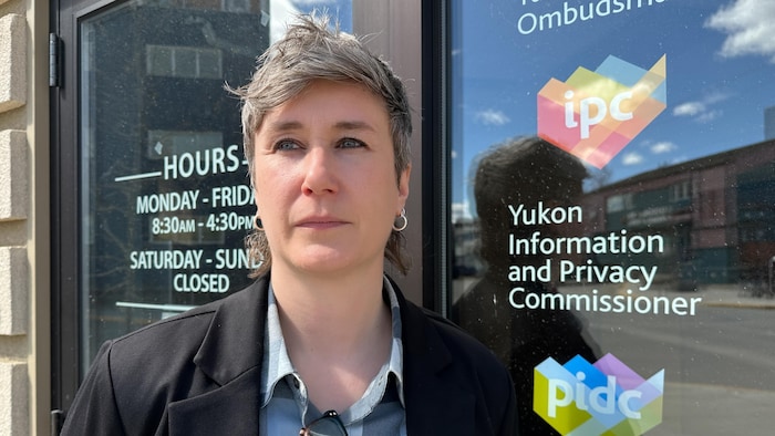 Une femme pose devant l'édifice qui abrite les bureaux du Commissariat à l'information et à la protection de la vie privée pour le Yukon.