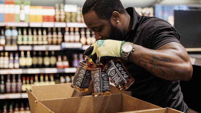 Une personne met des alcools américains dans un carton