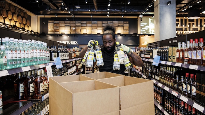 Un employé d’un magasin LCBO de Toronto met des bouteilles d’alcools américains dans une boîte de carton après les avoir retirées des rayons le 4 mars 2025. 