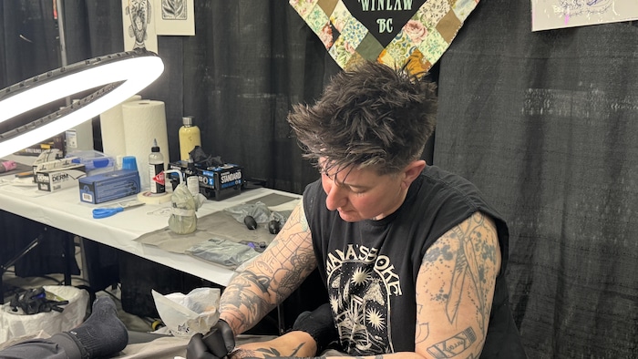 Sylvie Le Sciellier tatoue la jambe d'une cliente.