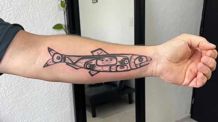 Un bras tendu sur lequel est tatoué un poisson.