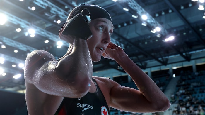La nageuse ajuste son casque de bain en sortant de l'eau.