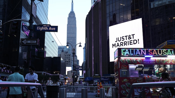 Un écran géant lumineux affiche le message « JUST&T MARRIED! » tandis qu'on voit l'Empire State Building en arrière-plan.