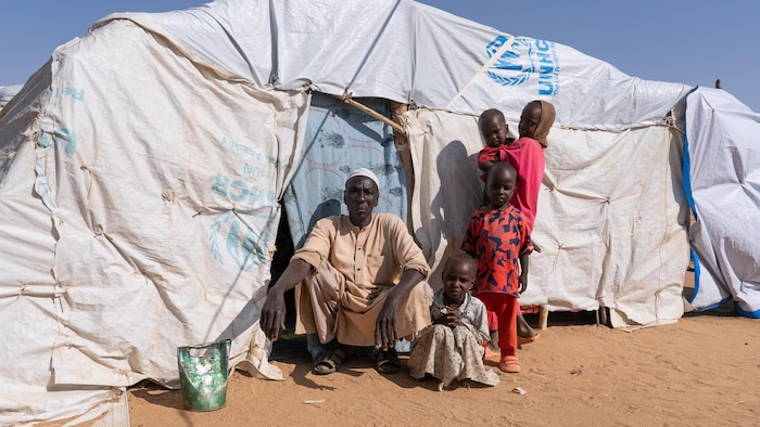 Mahamat Abdallah devant sa tente de fortune avec une partie de sa famille.