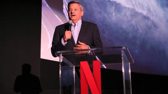 L'homme tient un micro et parle sur une scène.