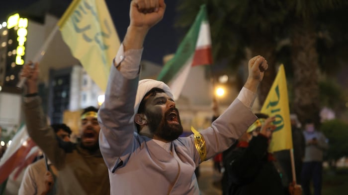 In the streets, Iranians demonstrate with flags and weapons in the air. 