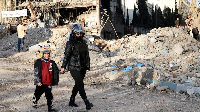 Une mère iranienne et son fils marchent près des décombres à Téhéran.