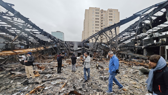 Des photographes prennent des clichés d'un garage automobile étranger détruit lors d'une attaque conjointe menée par les États-Unis et Israël le 28 mars 2026 à Téhéran, en Iran. 