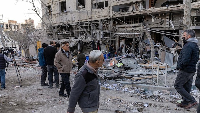 Des personnes observent les dégâts causés aux magasins et aux habitations détruits.