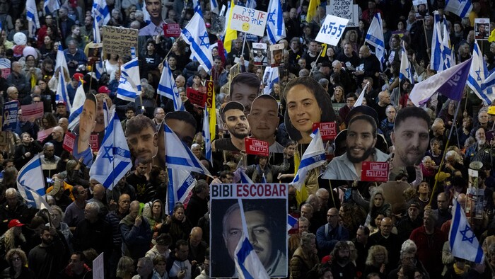 Des manifestants brandissant des drapeaux, des portraits et des pancartes.