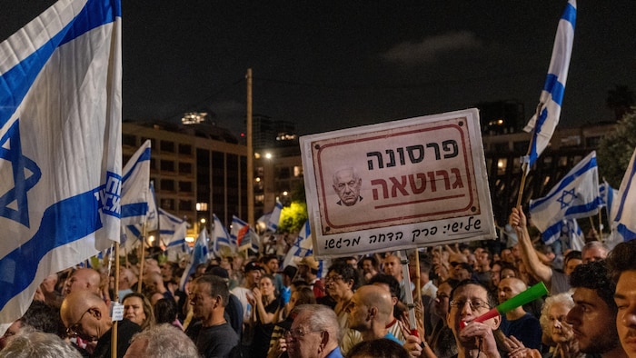 Une foule de manifestants brandit des pancartes et des drapeaux israéliens.