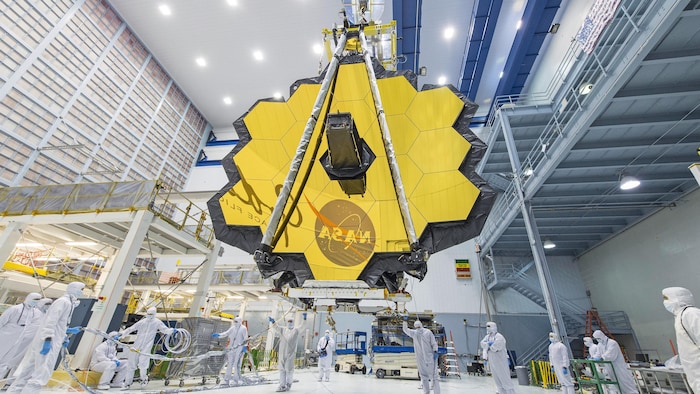 Des techniciens soulèvent l'assemblage du miroir du télescope spatial James Webb.