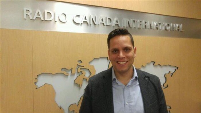 Marc Bustamante pose devant l'entrée des bureaux de Radio Canada International.