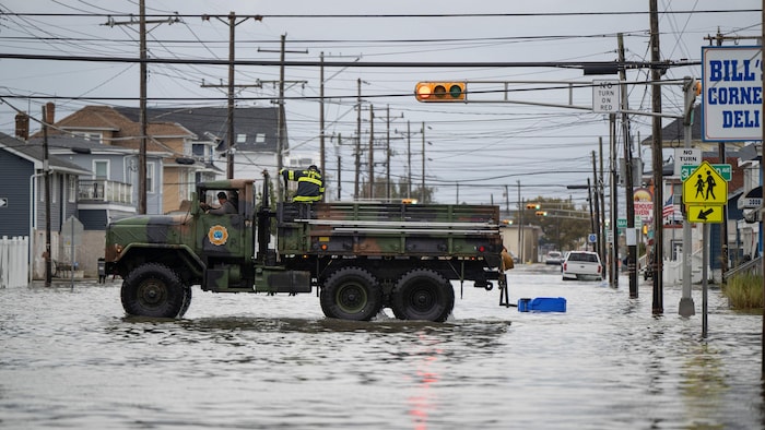Des pompiers circulent dans une rue inondée.