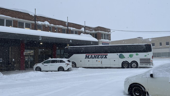 Un autocar des Autobus Maheux stationné à son terminus sur un sol enneigé.