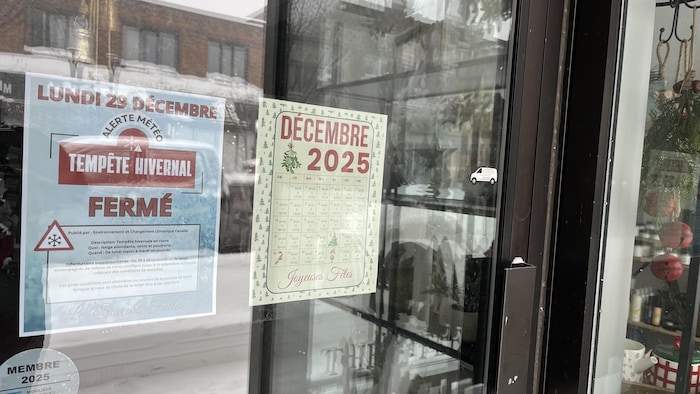 Une affiche dans une vitrine indiquant que le commerce est fermé pour la journée à cause d'une tempête hivernale.