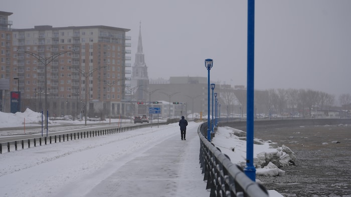 Une personne marche sur la promenade de la mer à Rimouski.