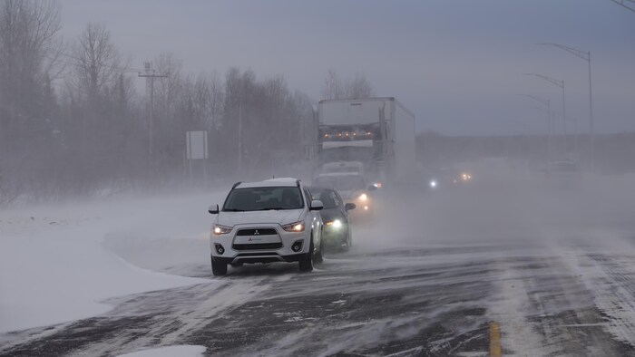 Une file de véhicules en pleine tempête de neige.