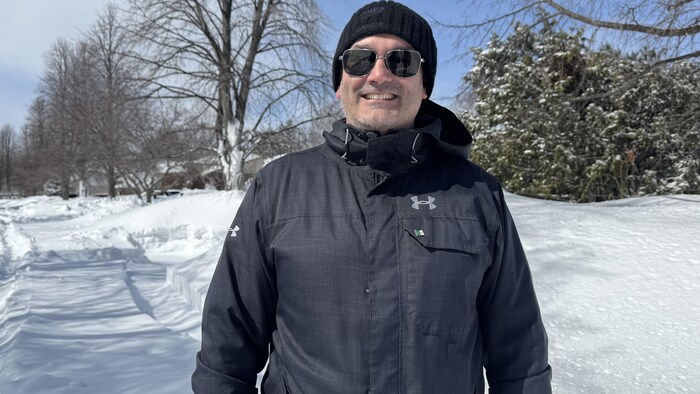 Un homme en manteau et en lunettes dans la neige.