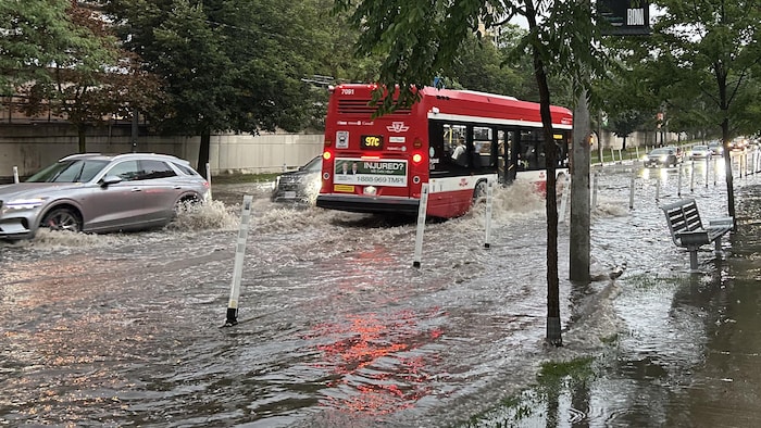 Un autobus circule dans une rue inondée.