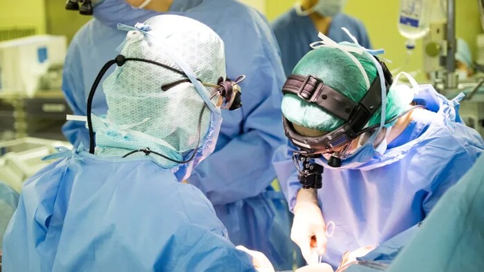 Des chirurgiens et leurs assistants dans une salle d'opération.
