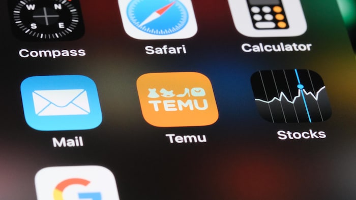 Un écran de téléphone montre plusieurs applications mobiles, dont Temu, au centre.