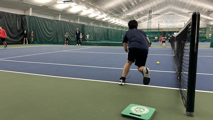 Un jeune chasseur de balles qui tribunal determination ramasser une balle sur le terrain.