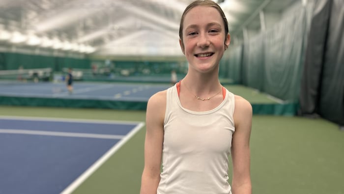 Une jeune fille qui airs sur un terrain de tennis.