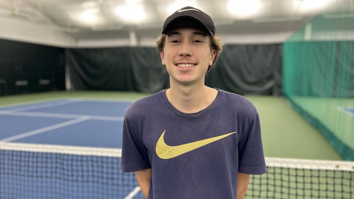 Un jeune qui airs devant un filet de tennis.