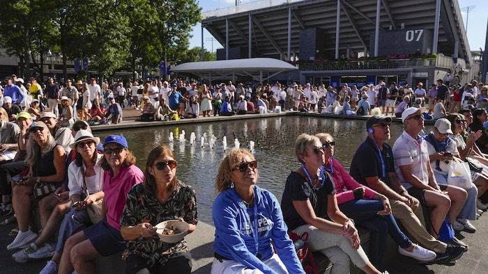 Des amateurs de tennis regardent un match du troisième tour sur l’écran géant à l’extérieur du stade Arthur-Ashe, lors des Internationaux des États-Unis, le vendredi 29 août 2025, à New York.