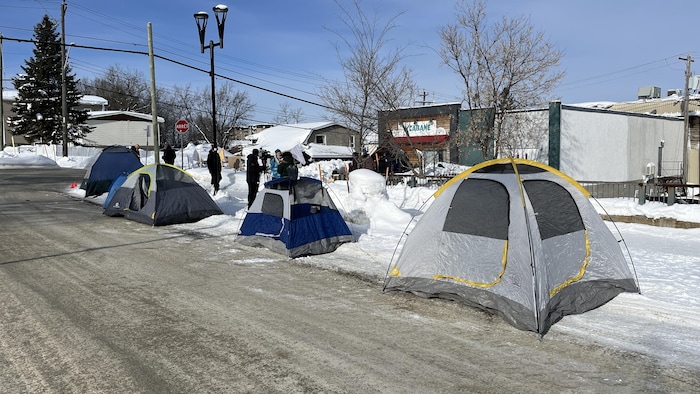 Des tentes installées sur le bord du chemin en hiver.