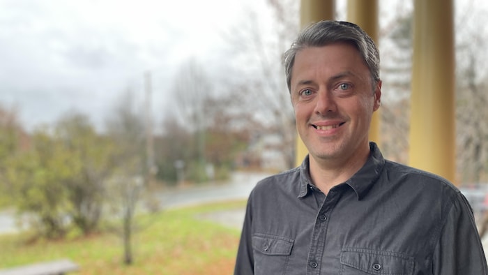 Un homme souriant à la caméra.