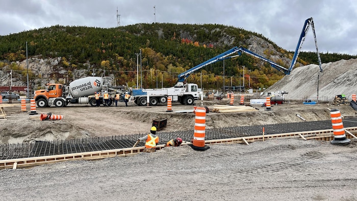 Des ouvriers travaillent sur le chantier de construction du terminal no 5 avec une bétonnière et une pompe à béton.