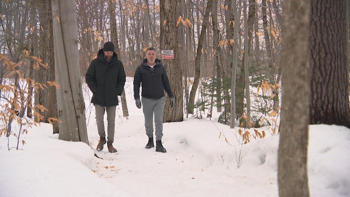 Deux hommes marchent dans le bois.