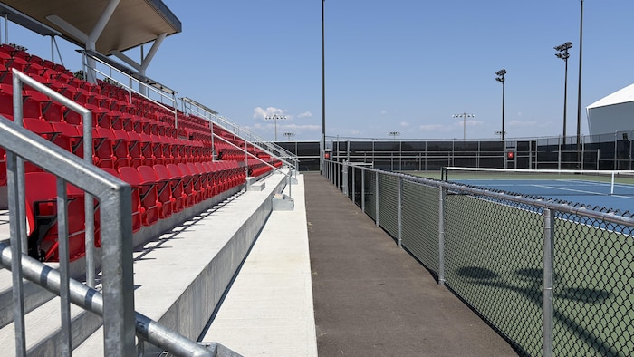 Des estrades aux abords d'un terrain de tennis extérieur.