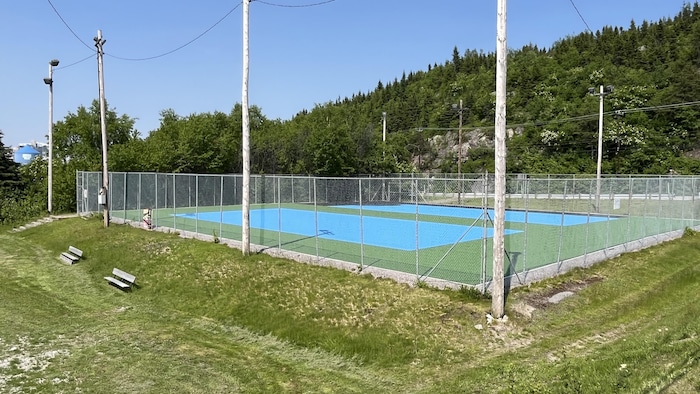 Deux terrains de tennis extérieurs sont fraîchement peints en bleu.