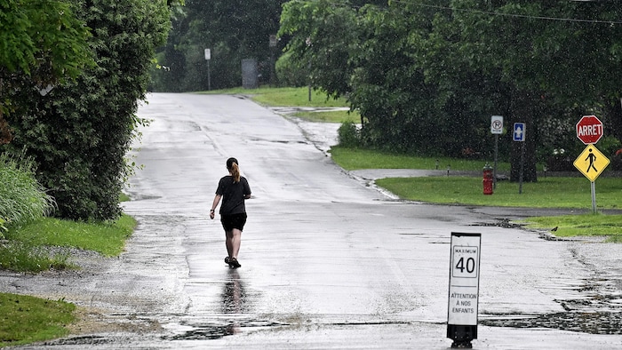 Une femme marche sous la pluie, à Terrasse-Vaudreuil, à l'ouest de Montréal.