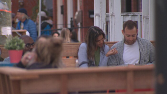 Un couple regarde un menu dans le Vieux-Hull et des clients sont attablés sur les terrasses des restaurants de la rue Laval. 