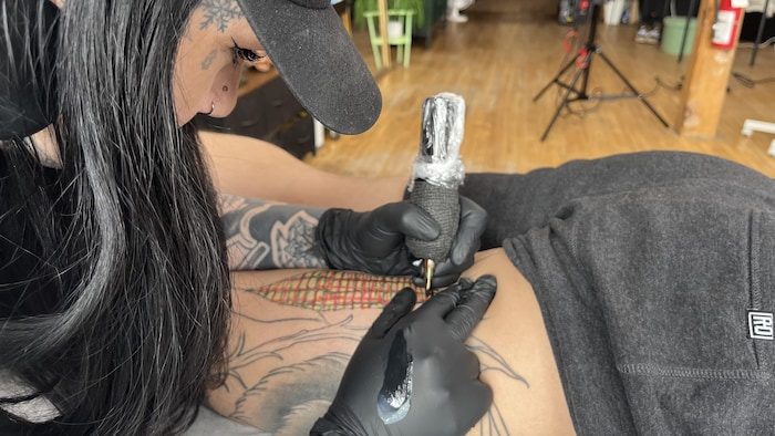 Une femme en train de tatouer un épi de maïs. 