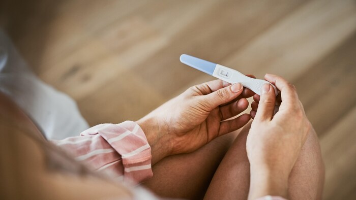 Une femme tient un test de grossesse négative dans ses mains