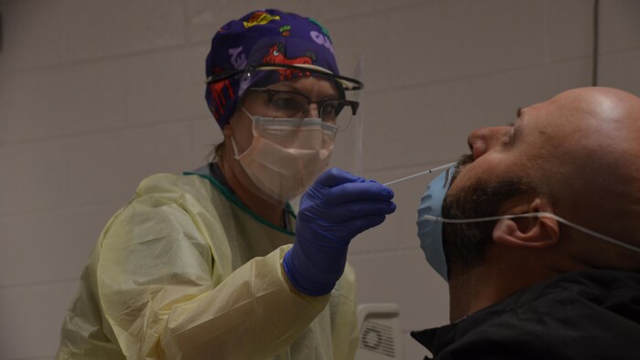 Une infirmière fait un prélèvement dans la cavité nasale d'un patient.