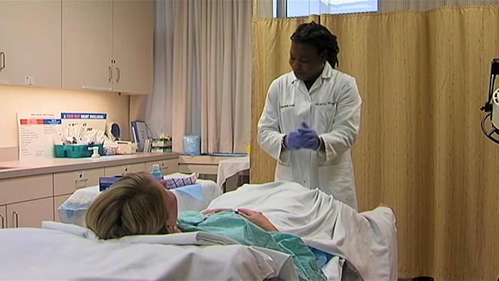 Une médecin devant une patiente couchée sur un lit d'hôpital.
