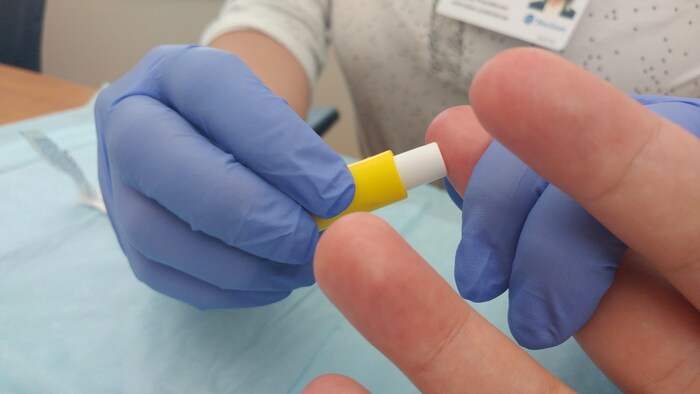 Un doigt se fait piquer pour prendre un échantillon de sang. 