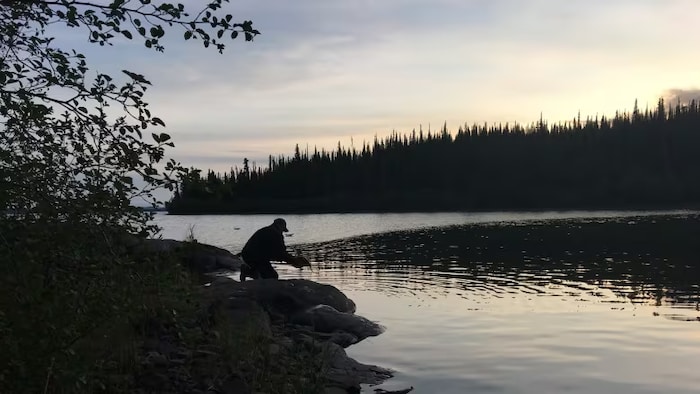 Un homme devant un lac.