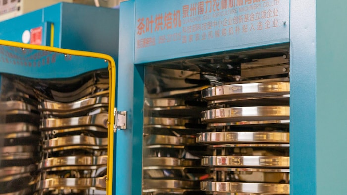 Des inscriptions dans une langue asiatique ornent le devant de la machine. La porte est ouverte et donne lieu à des séchoirs en forme de cercle.