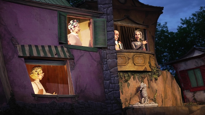 Un décor théâtral où se trouvent des marionnettes géantes.