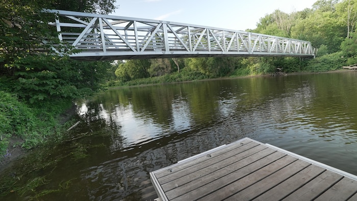 Une passerelle passe au-dessus d'une rivière calme.