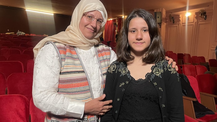 Une femme posant à côté de sa fille de 12 ans.